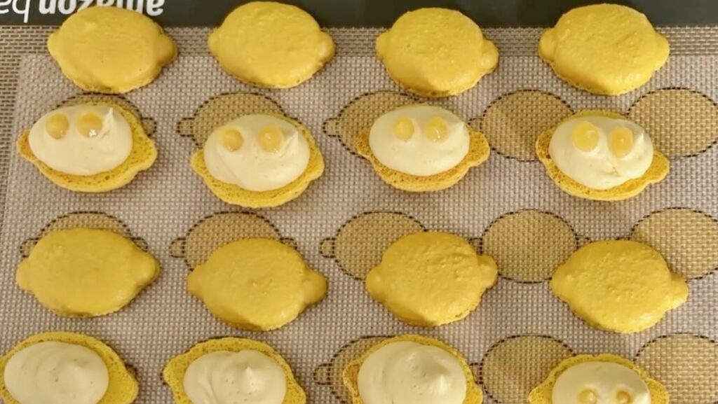 Lemon Macarons being filled with lemon curd macaron filling and lemon white chocolate ganache