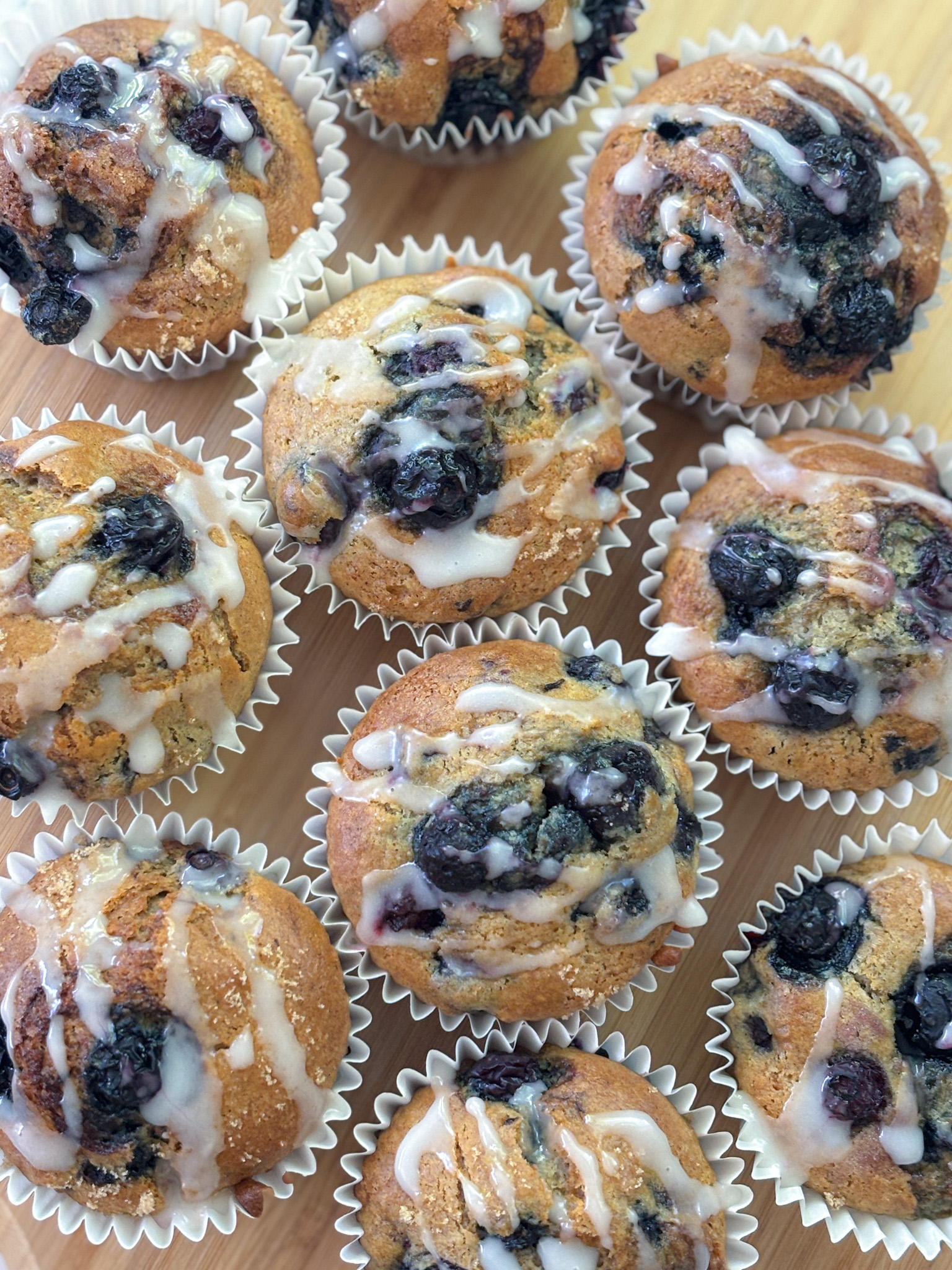 Fresh batch of quick and easy Blueberry banana muffins in cases with lemon icing drizzle