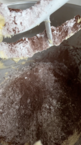 Icing Sugar and cocoa powder addition step of making chocolate fudge buttercream. Icing sugar, butter and cocoa powder in bowl