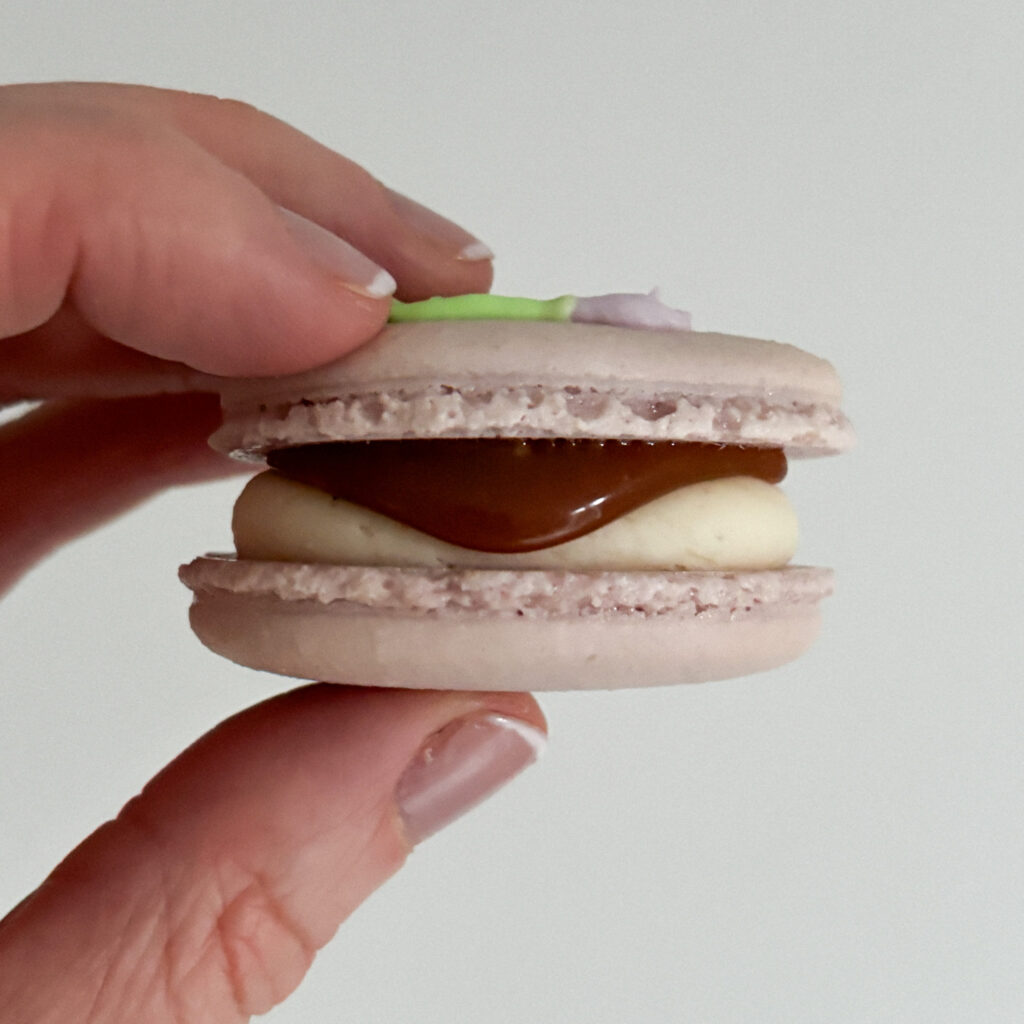 Hand holding caramel macaron
