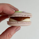 Hand holding caramel and buttercream filled macaroon