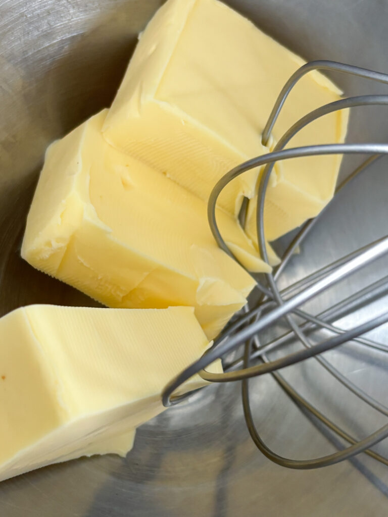 Blocks of butter in kitchen aid stainless steel mixing bowl with whisk