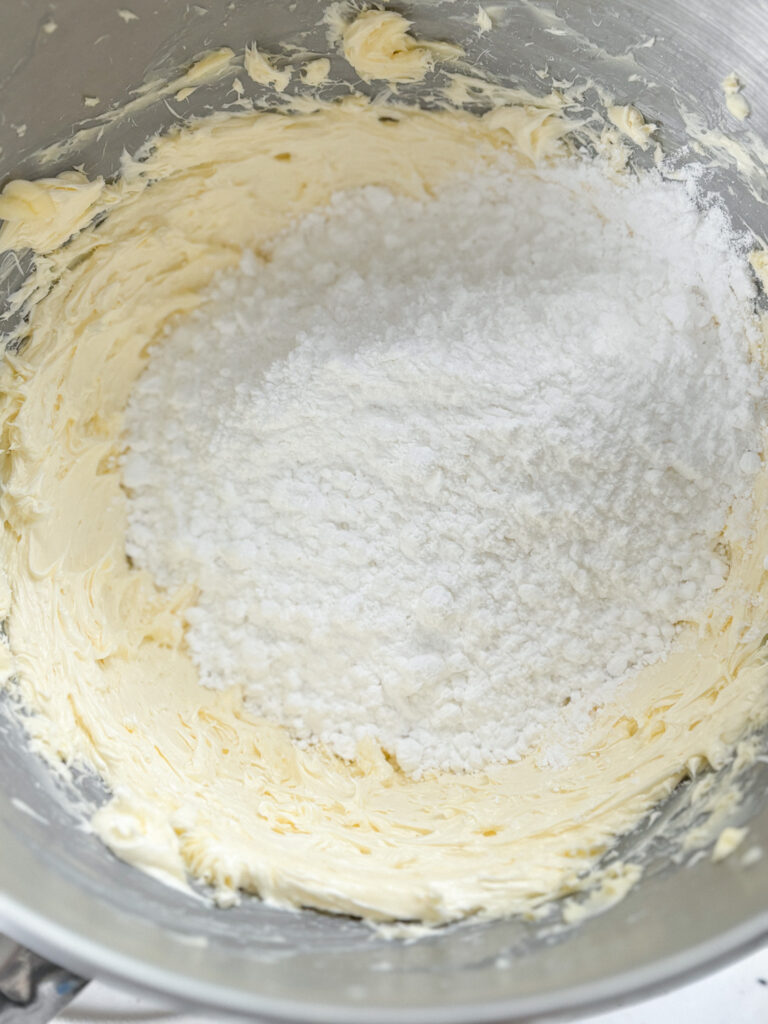 Whisked butter in bowl with icing sugar added - Vanilla Buttercream Macaron Filling recipe step