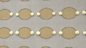 Lemon macaron batter being piped onto parchment paper with a piping bag - Recipe tutorial